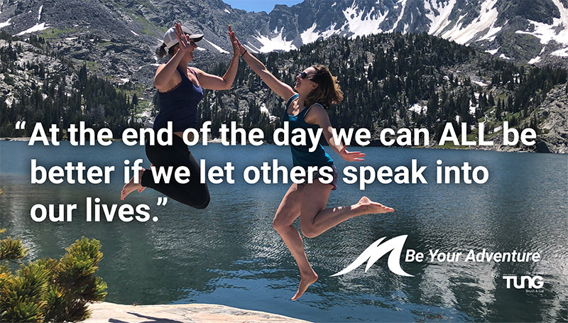 Girls high-fiving near a mountain lake